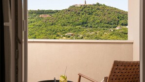 A balcony with a view of a hill, a chair, and a small table with a drink. - Amazing home in Labin - Rabac (Labin - Rabac)