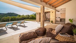 A covered outdoor area with a pool, lounge chairs, and a seating area with cushions. - Amazing home in Labin - Rabac (Labin - Rabac)