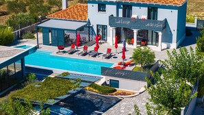 Un edifici modern de dos pisos amb piscina, espai d'estar a l'exterior i terrassa coberta.
