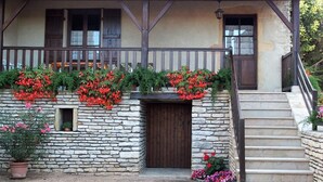 A stone building with a tiled roof, wooden porch, and a staircase leading to the entrance. - Les Cadoles - Cortevaix (CORTEVAIX)