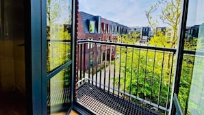 A balcony with a metal railing overlooking a courtyard with buildings and trees. - Chasse Residency Hotel (Amsterdam)