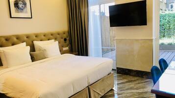 Une chambre d’hôtel avec un grand lit, un téléviseur à écran plat fixé au mur et une vue sur la verdure.