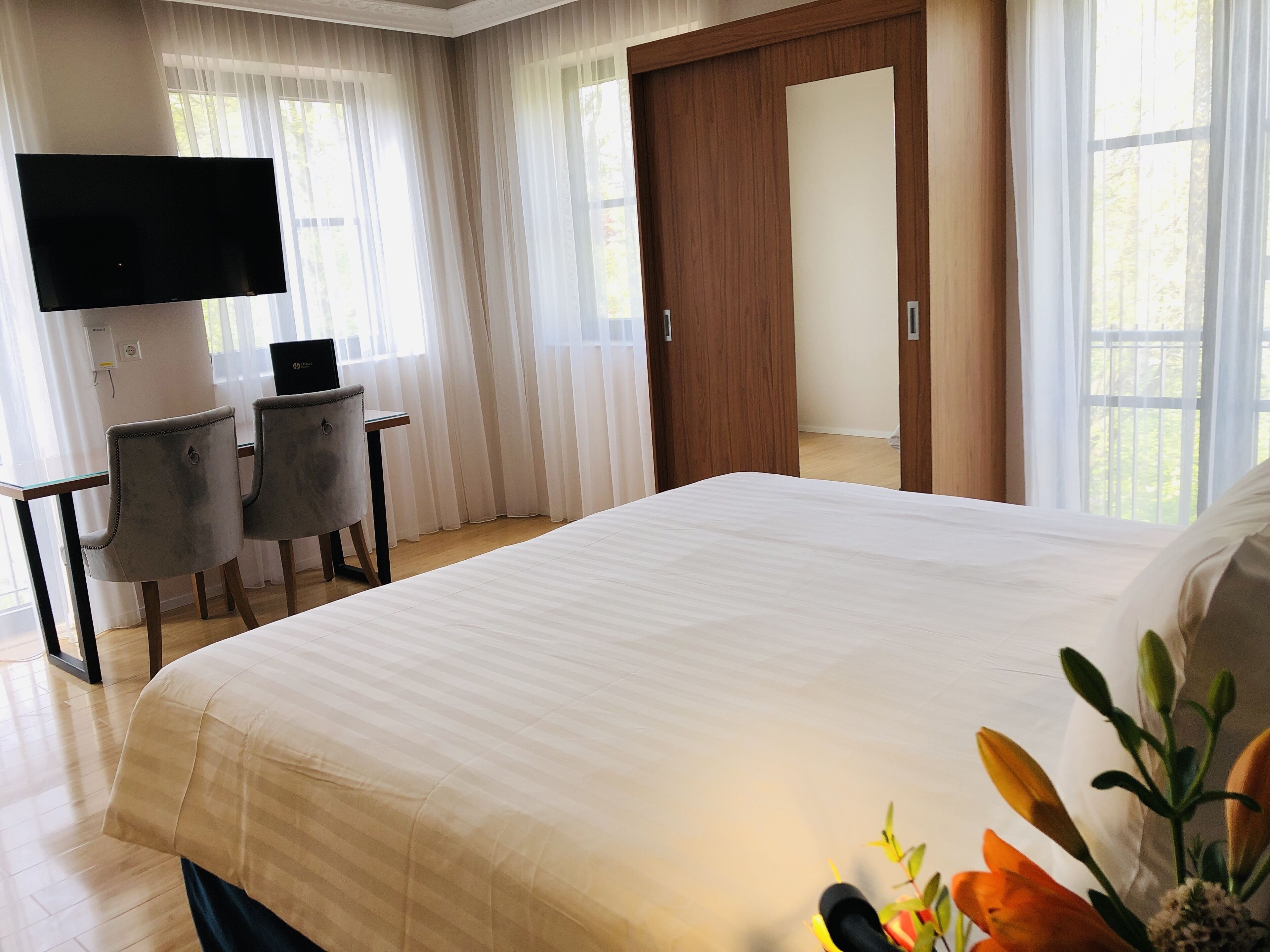 Habitación de hotel con una cama grande, un escritorio con silla, un televisor de pantalla plana y una puerta de madera.
