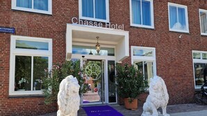 The Chase Hotel entrance with a purple welcome mat, two white lion statues, and a brick facade. - Chasse Residency Hotel (Amsterdam)