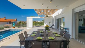 An outdoor dining area with a pool, a covered patio, and a view of the surrounding neighborhood. - Stunning home in Porec (Porec)