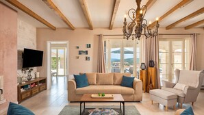 A spacious living room with a beige sofa, a wooden coffee table, and a television mounted on the wall. - Nice home in Porec with sauna (Porec)