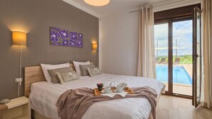 A bedroom with a large bed, a view of a swimming pool, and a sunset visible through the window. - Amazing home in Gracisce (Gracisce)