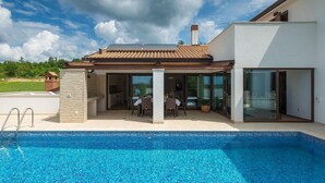A modern house with a swimming pool, a patio with outdoor furniture, and a large glass door leading to a covered outdoor area. - Amazing home in Gracisce (Gracisce)