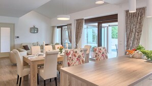 A dining area with a wooden table, white chairs, and floral-patterned cushions. There are curtains on the windows, and a clock is visible on the wall. - Amazing home in Gracisce (Gracisce)