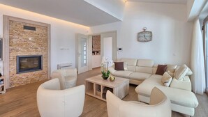 A modern living room with a stone accent wall, a fireplace, a sofa set, and a clock on the wall. - Amazing home in Gracisce (Gracisce)