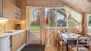 Une cuisine de taille réduite avec des murs en bois, un évier, une machine à café et une table avec des chaises.