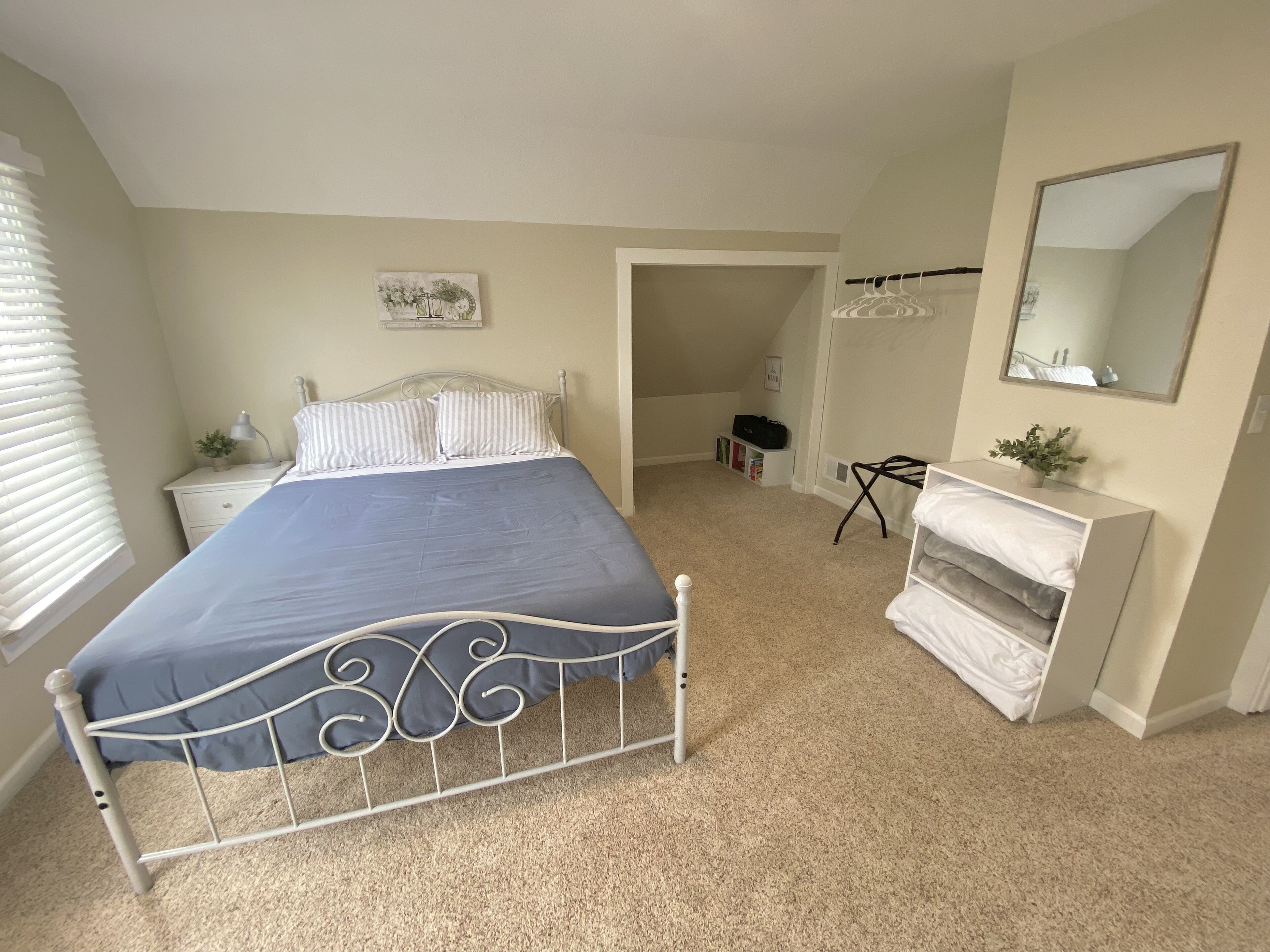 A bedroom with a bed, bedside table, lamp, and a dresser.