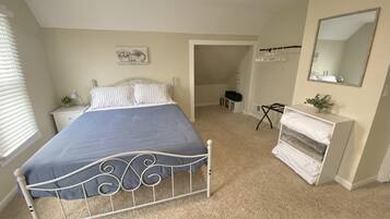 A bedroom with a bed, bedside table, lamp, and a dresser.