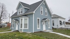 A two-story house with a gabled roof, a front porch, and a small front yard. - Charming Family Retreat - 15 min to Nauvoo & Carthage (Hamilton)