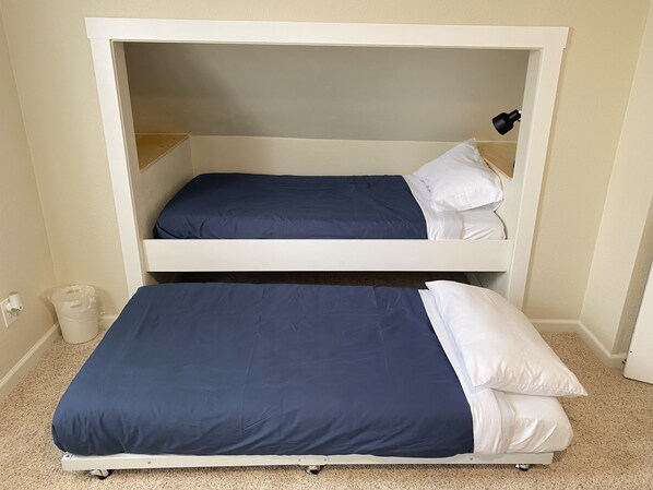 A bunk bed with two levels, each with a blue mattress and white pillows.