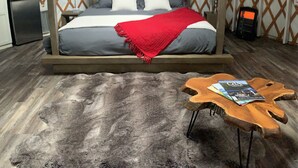 Una habitación con cama con dosel, una manta roja, una mesa de centro de madera con revistas y un diseño de techo singular.