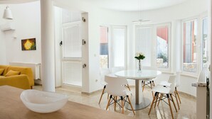 A bright, modern dining area with a round table, white chairs, and a vase of flowers. - Amazing home in Murter with sauna (Murter)