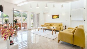 A modern living room with a yellow sofa, two white coffee tables, and a large window with a view of greenery. - Amazing home in Murter with sauna (Murter)