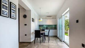 Une cuisine moderne avec un coin repas, dotée d’une grande fenêtre, d’une horloge et de tableaux encadrés au mur.