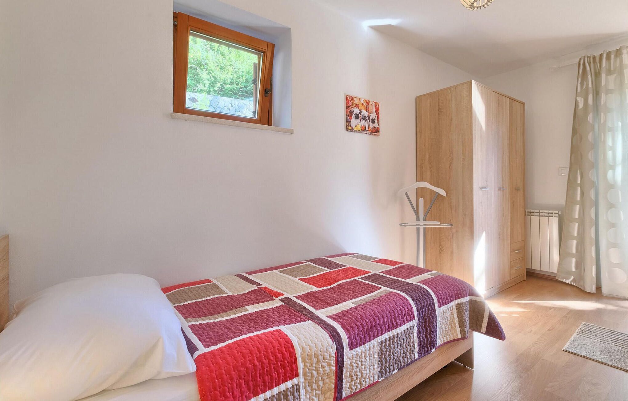 A bedroom with a bed, a window, a wardrobe, and a radiator.