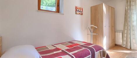 A bedroom with a bed, a window, a wardrobe, and a radiator.