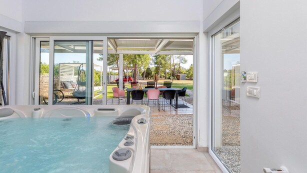 Un área de spa con hidromasaje y una terraza con mobiliario exterior.