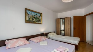 Quarto com duas camas, um quadro na parede, um guarda-roupa e uma porta.
