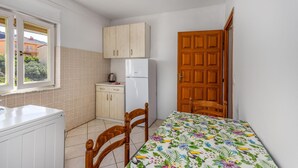 Uma cozinha compacta com geladeira, armários de madeira, uma janela com vista e uma porta de madeira.