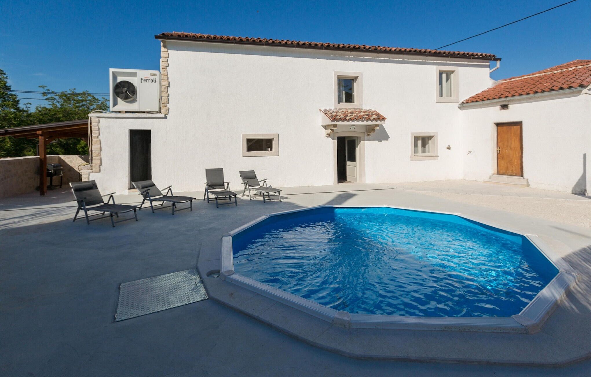 A white villa with a swimming pool, outdoor seating, and a pergola.