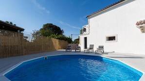 A swimming pool with lounge chairs and a white building with a clock. - Amazing home in Tinjan (Tinjan)