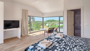 A modern bedroom with a large bed, a TV, a balcony with a chair, and a shower area. - Awesome home in Novigrad (Novigrad)