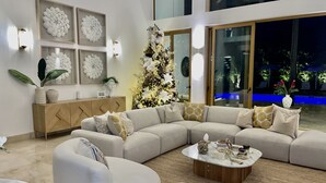 Una sala de estar moderna con un amplio sofá modular, una mesa de centro redonda y decoración en la pared.