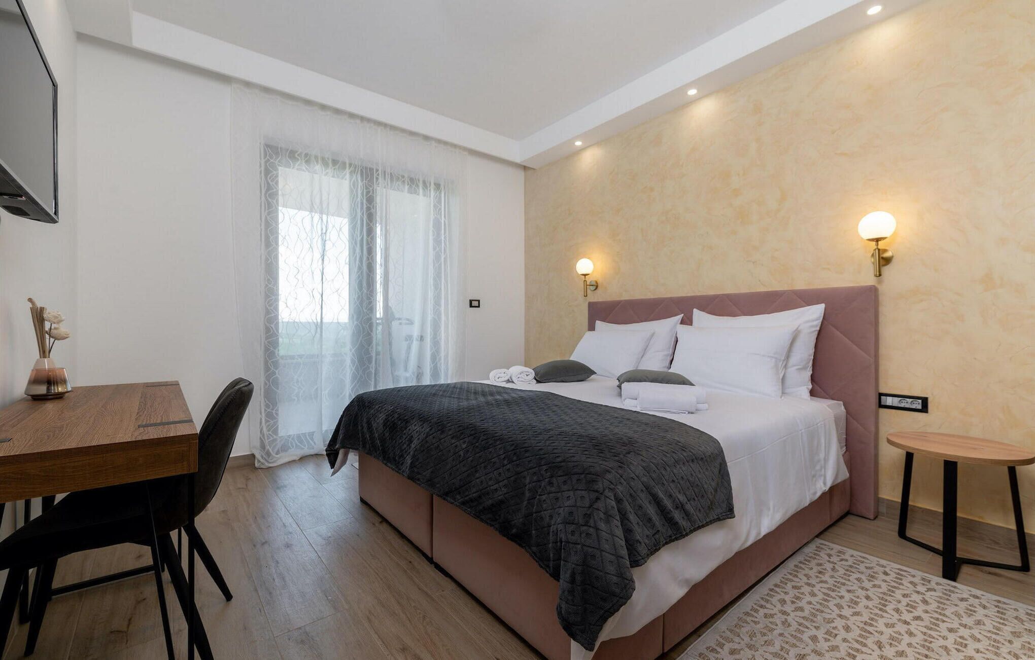 Ett modernt hotellrum med en säng, sängbord, ett skrivbord och en stol.