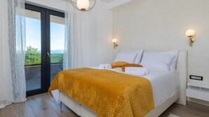 Une chambre d’hôtel avec un lit, une vue par une porte coulissante et un luminaire au plafond.