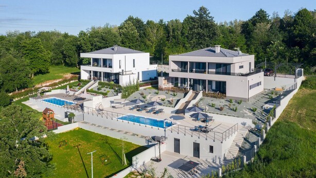Une maison moderne à deux étages, dotée d’une piscine, d’un espace extérieur aménagé et d’un jardin bien entretenu.