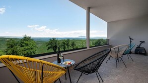 Un balcon avec une table, des chaises et un vélo d’exercice.