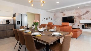 Un espace repas moderne avec une table rectangulaire dressée pour quatre personnes, entourée de chaises à revêtement marron.