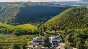 Une maison moderne, dotée d’un toit en pente, entourée de collines verdoyantes et d’une vallée.