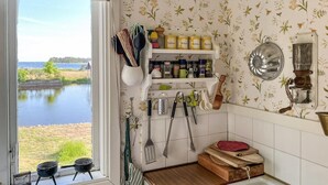 Ett kök med utsikt över en sjö, träskärbrädor, ett rivjärn och köksredskap som hänger på väggen.