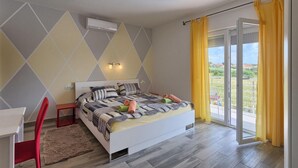 A bedroom with a bed, a desk, and a chair. There is a window with yellow curtains and a view of the outside. - Amazing home in Porec (Porec)