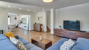 A modern living room with a sofa set, a coffee table, and a TV. There is a kitchen area with white cabinets and a dining table visible in the background. - Beautiful home in Umag (Umag)