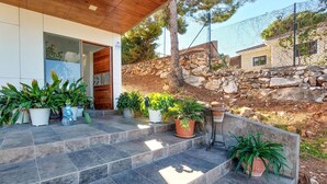 Une maison moderne avec un mur en pierre et des plantes en pot disposées sur les marches.