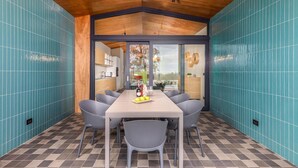 A modern kitchen with a large dining table, grey chairs, and a view of the outdoors through a glass door. - Amazing home in Vodnjan with private swimming pool, can be inside or outside (Vodnjan)