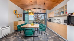 A modern kitchen with a wooden ceiling, a dining area with green chairs, and a view of the outdoors. - Amazing home in Vodnjan with private swimming pool, can be inside or outside (Vodnjan)