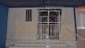 Un escalier recouvert de carreaux de marbre menant à une porte surmontée d’un portail en métal.