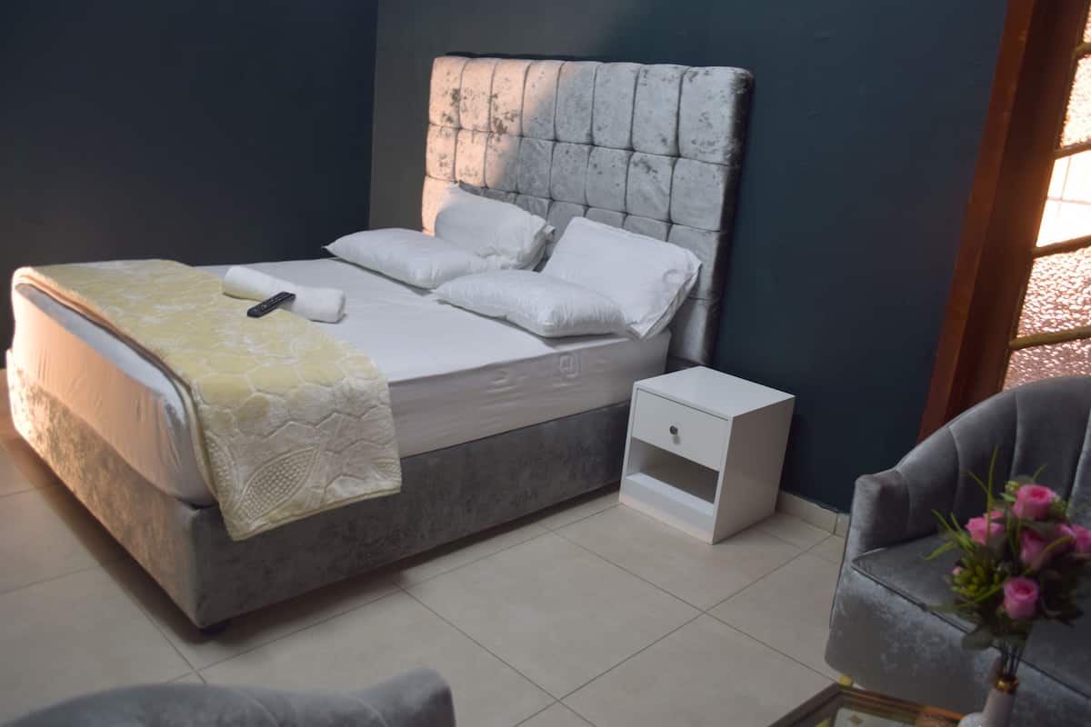Een slaapkamer met een bed, nachtkastje en een stoel.