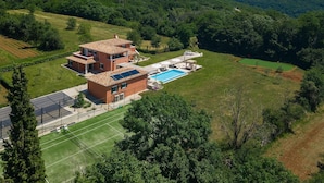 A two-story house with a swimming pool, surrounded by lush greenery and a golf course. - Amazing home in Tinjan with sauna (Tinjan)