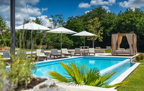 A swimming pool with lounge chairs and umbrellas, surrounded by greenery and a gazebo. - Amazing home in Tinjan with sauna (Tinjan)