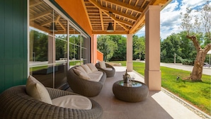 A covered outdoor seating area with wicker furniture and a glass enclosure. - Amazing home in Tinjan with sauna (Tinjan)