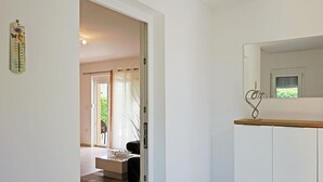 A hallway with a door leading to a room, a thermostat on the wall, and a decorative metal piece on a cabinet.